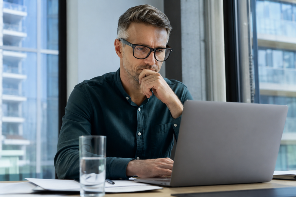 Mann sitzt nachdenklich am Laptop und plant eine Umschulung wegen KI für seine berufliche Zukunft